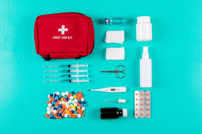 Flat lay first aid kit with pills, thermometer, spray, pills and bandage on cyan blue background